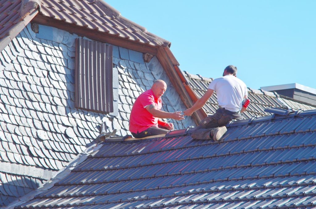 two-men-working-on-the-roof-of-a-house-skicvm6sptu